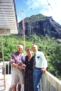 Jukka VP6BR/OH2BR presents the pennant of the SRAL to his hosts Betty VP6YL and Tom VP6TC. In the background is the rugged skyline in the are of Fletcher Christian's Cave. You can see the 6 meter yagi in its new locatuib at Tom's QTH.